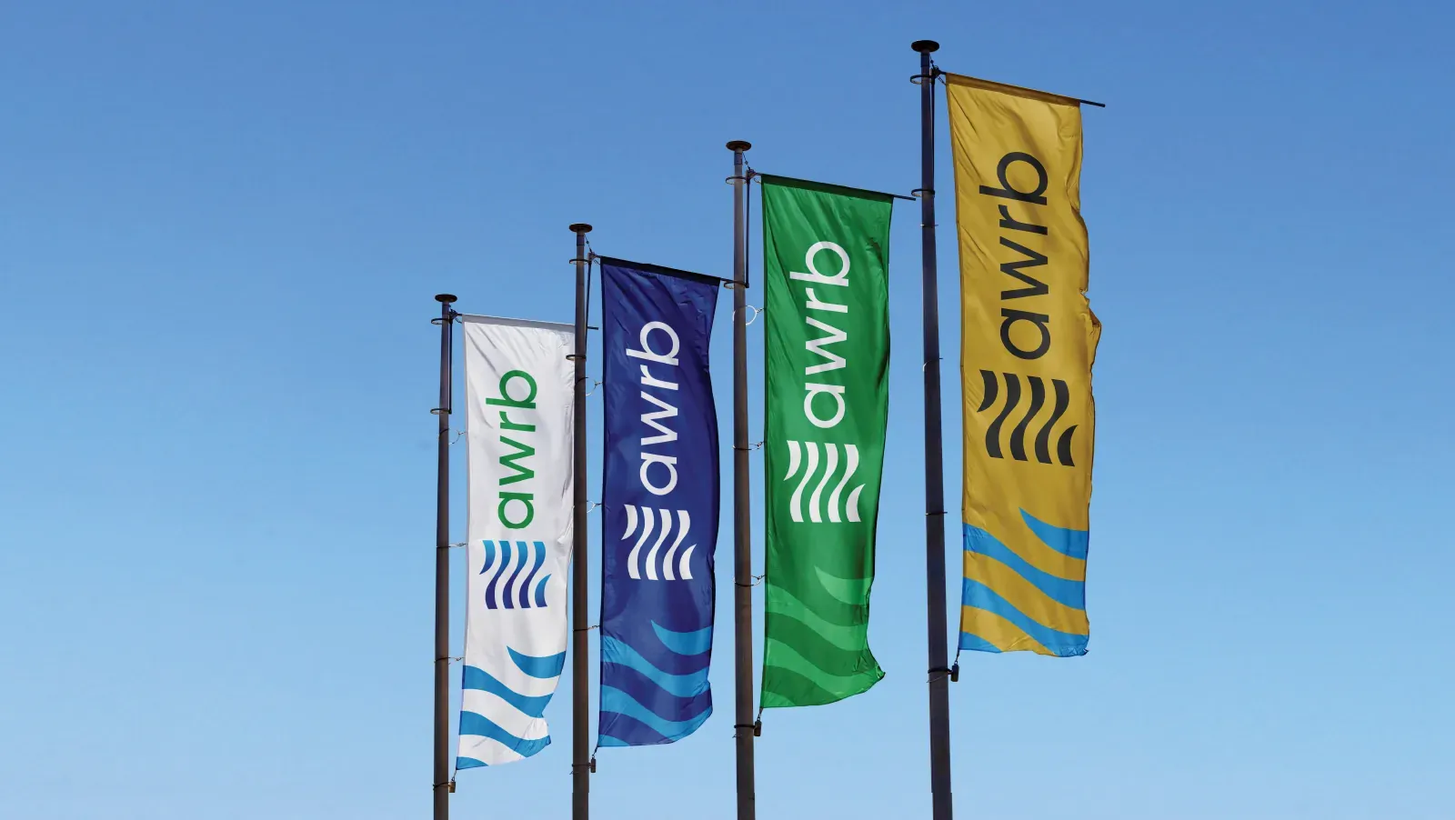 Four Ankobra flags in white, navy, green and gold against a blue sky.